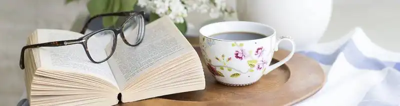 Wissen zur Aloe Vera Pflanze - Bild mit einem Buch einer Brille darauf und einer Teetasse nebenbei auf einem Holztablett